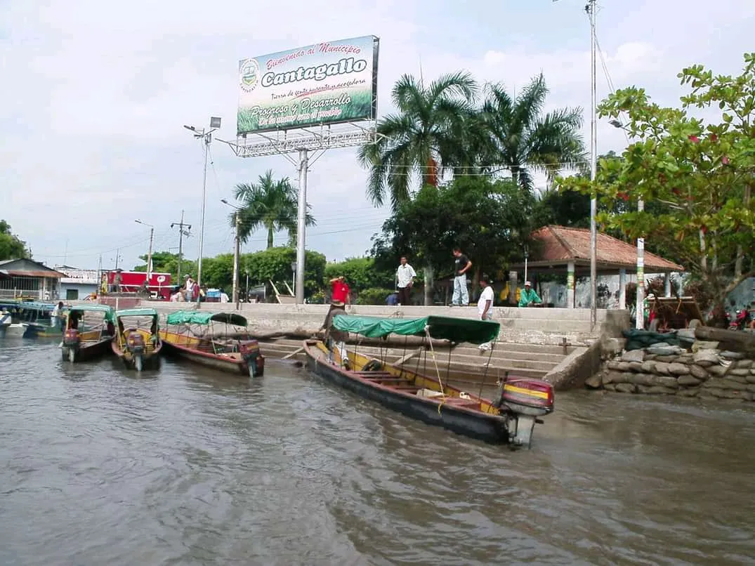 Antiguas canoas de madera atracadas en el puerto de Cantagallo, junto a la valla de bienvenida al municipio